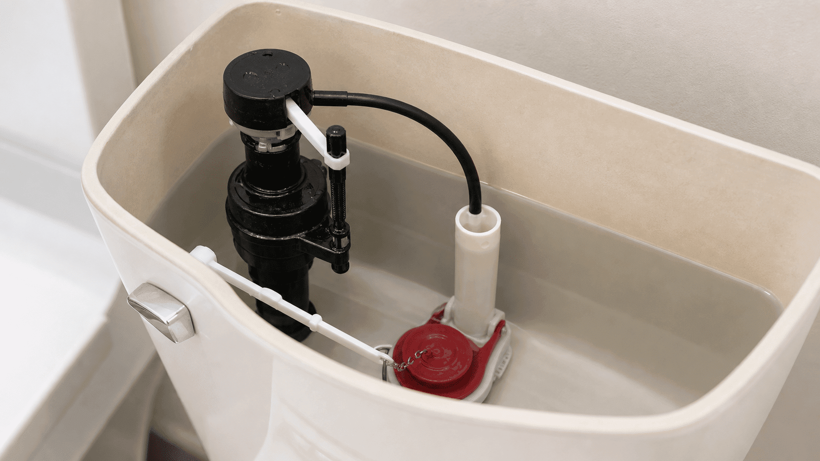 Toilet tank interior showing flapper fill valve and overflow tube components