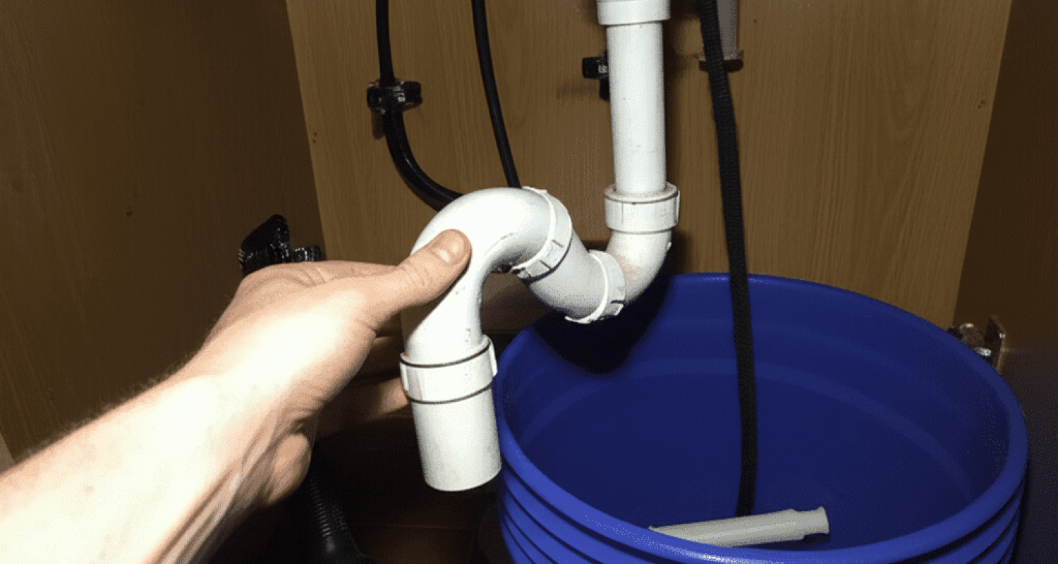 Removing and cleaning the P-trap under a kitchen sink to clear a drain clog